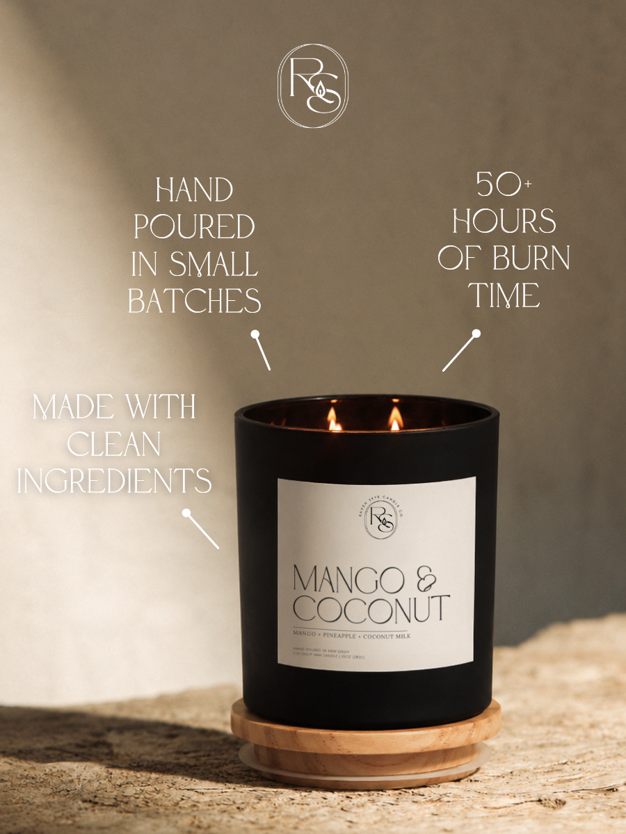 A black double-wick candle labeled 'Mango & Coconut' sits on a wooden base on a stone surface, with marketing text around it reading 'Hand poured in small batches,' '50+ hours of burn time,' and 'Made with clean ingredients.'.