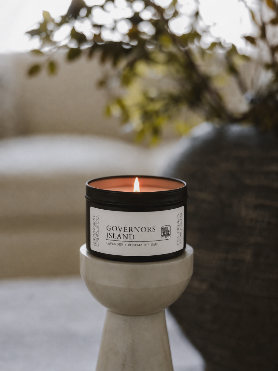 Candle labeled 'Governors Island' on a stone holder with a blurred outdoor background